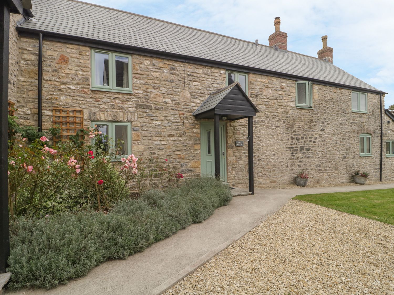 Stone exterior house with green framed windows and a green door with a front porch and garden at Dale Barton in Wells