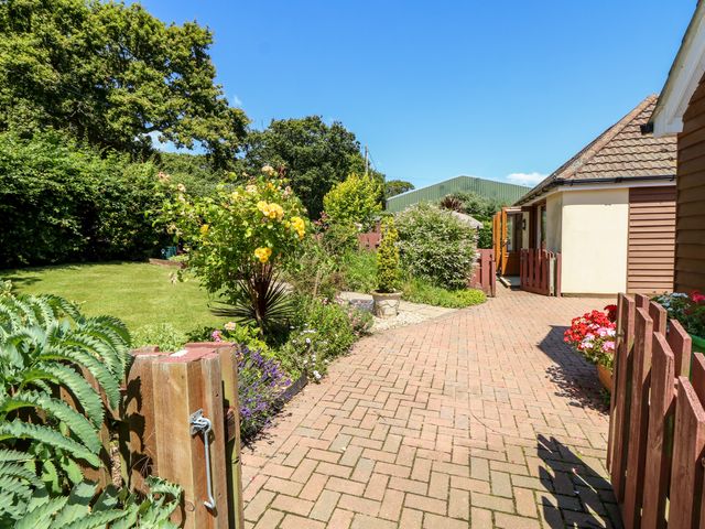 A garden with a brick path leading to a building surrounded by plants and flowers at 1 The Stables in Ryde