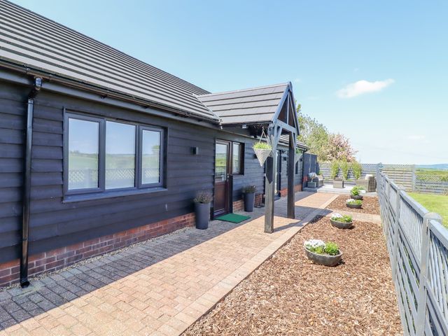An outdoor pathway with flower pots leading to the entrance of a black wooden house at Closefield in Ivinghoe Aston near Ivinghoe