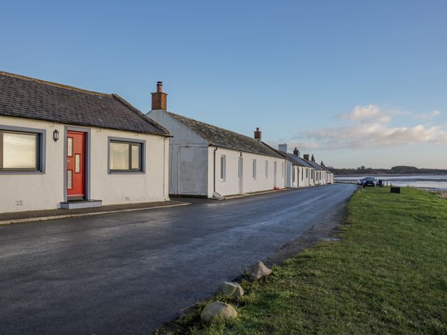 A row of white houses along a paved road near a grassy area and water at 2 Whiterow Powfoot Annan