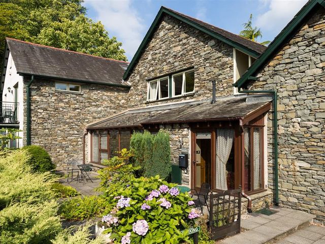 A stone house with patio furniture and flowering plants at The Gallery in Ambleside