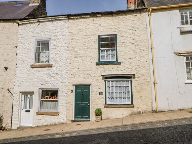 Stone facade cottages with green doors and windows on a sloped sidewalk at Dillons Cottage Richmond