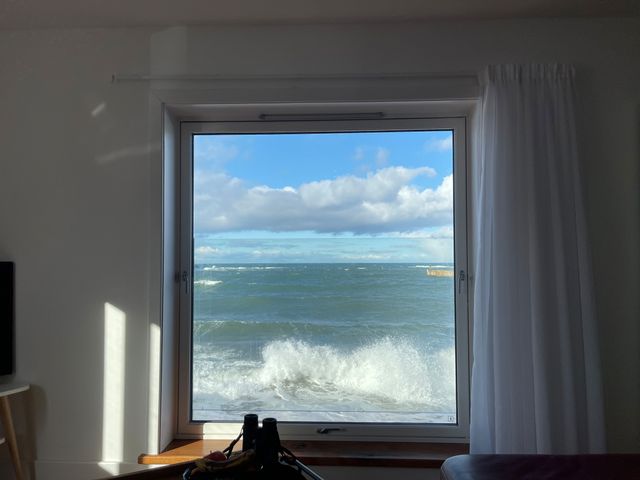 A window with a sea view and a pair of binoculars on the windowsill at Generals Yard in Eyemouth