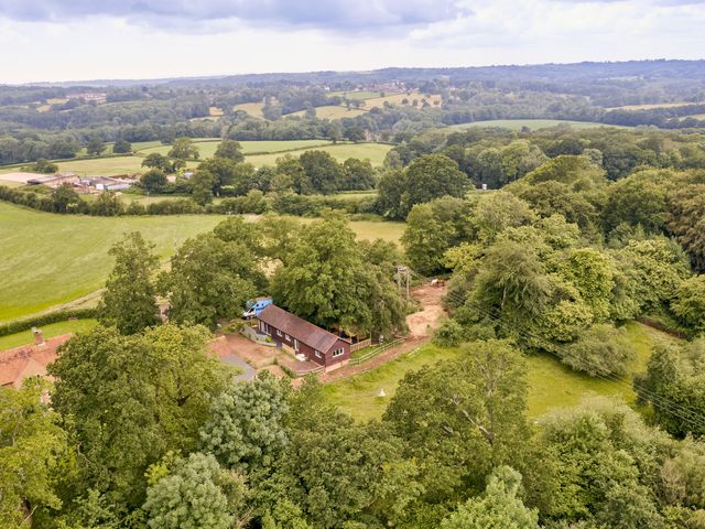 A rural farm area with trees fields and farm buildings at Forest Farm Cottage in Balcombe