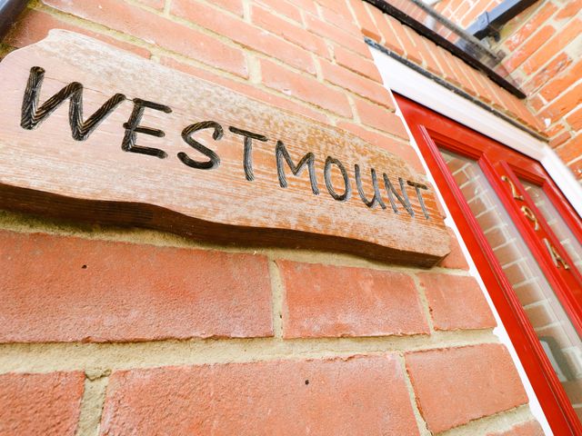A wooden sign with the word westmount on a red brick wall next to a red door at Westmount in Ryde