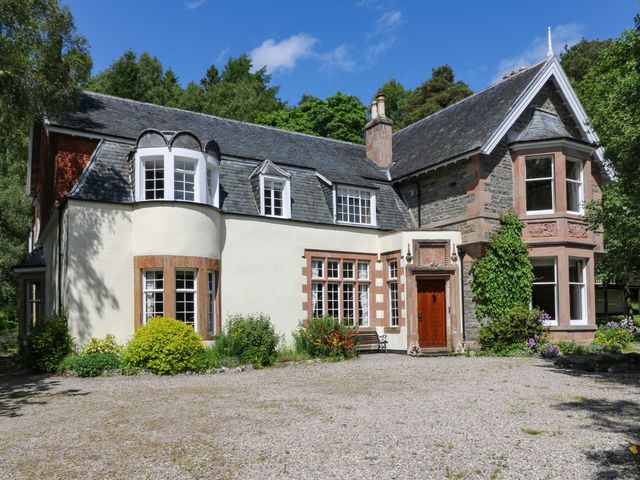 A house with stone and plaster walls windows a wooden door and a gravel driveway at Bearnock Lodge in Bearnock near Cannich