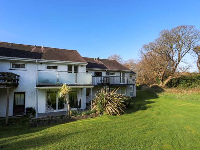 A house with balconies a green lawn and trees at Argoed in Y Felinheli