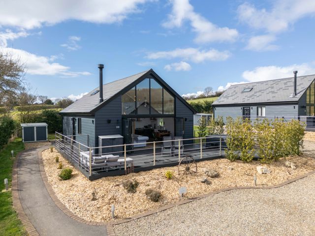 Two modern grey cabins with large glass windows and outdoor seating surrounded by a gravel and mulch garden at Foxes Den in Allerston near Thornton Dale