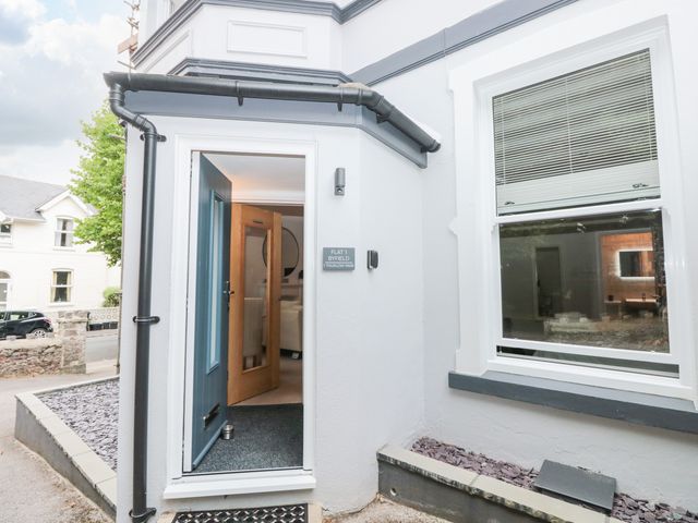 The entrance to a flat with an open blue door and gray exterior walls at Flat 1 Byfield in Torquay