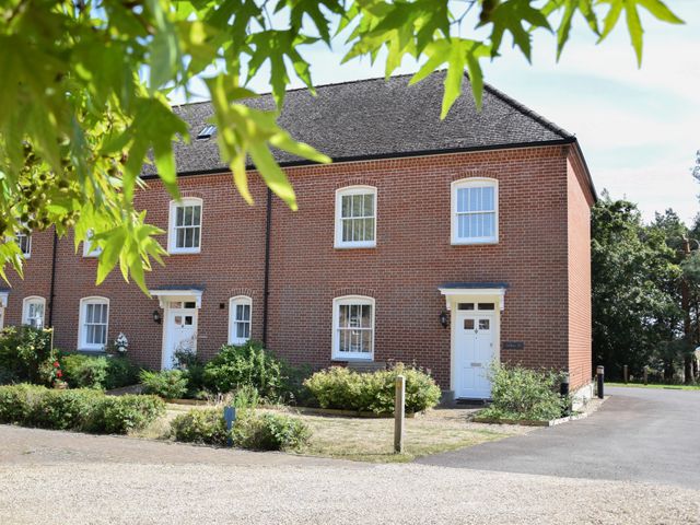 A brick residential house with white doors and windows surrounded by bushes and trees at The Gallery Blythburgh near Southwold