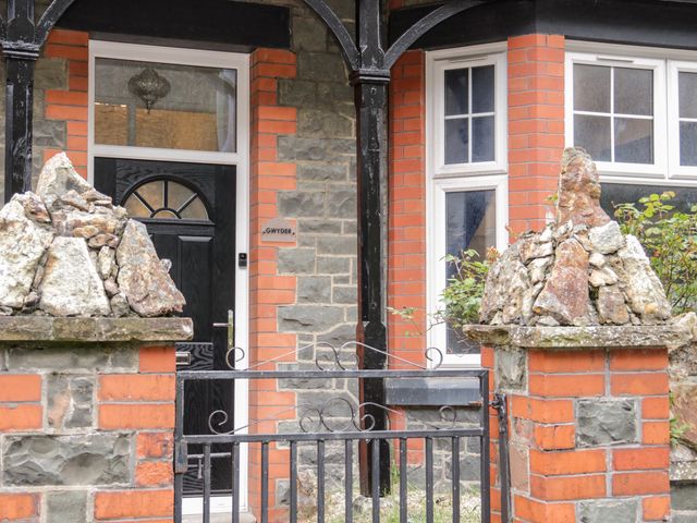 A front door with black metal gate and stone pillars at the entrance of a brick and stone house at Gwyder in Penmaenmawr