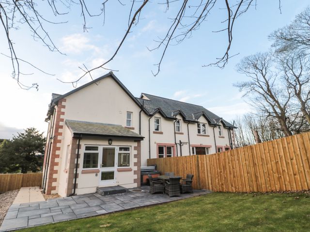 A backyard with a patio table and chairs next to a two-story house with a fenced garden at The Annexe in Berwick-Upon-Tweed