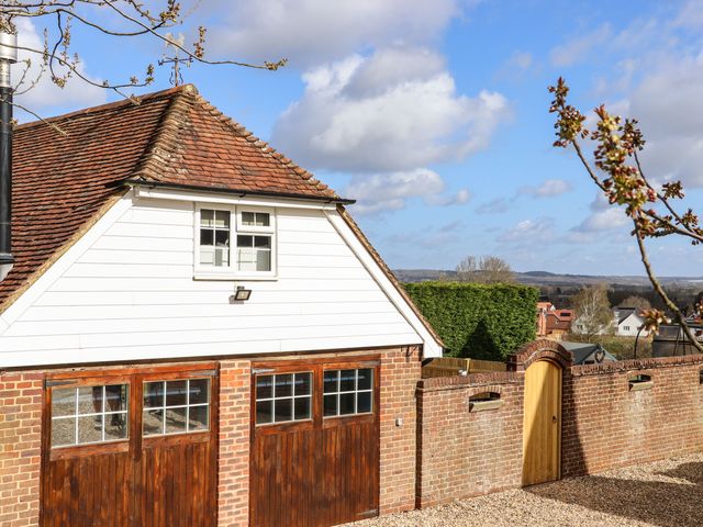 A brick garage with wooden doors and a tiled roof next to a brick wall with a wooden gate at Orchard Retreat in Paddock Wood Kent