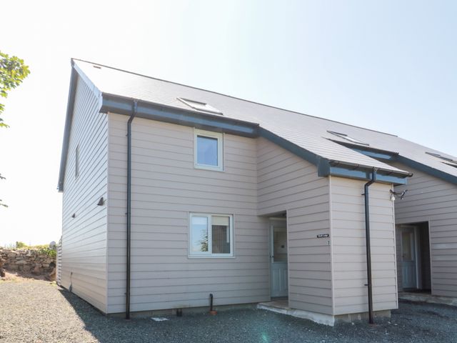 Exterior view of a beige two-story house with a sloped roof and multiple windows at Thrift Lodge in High Newton-by-the-Sea near Embleton