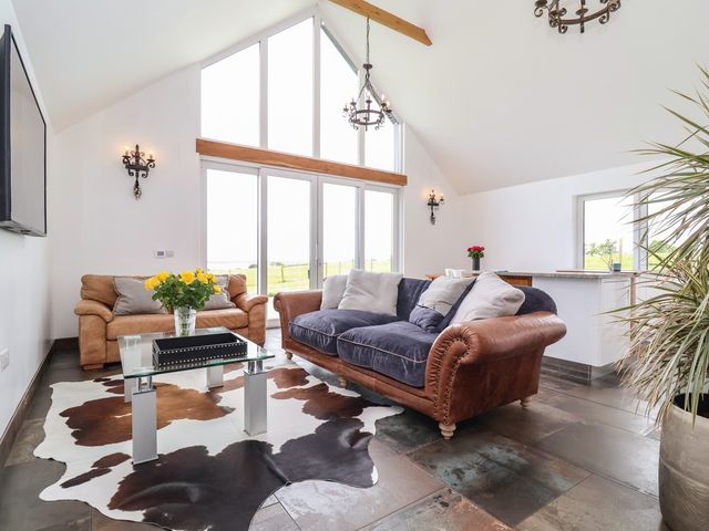 A living room with two sofas glass coffee table and large windows at Polly's Annexe in Levington