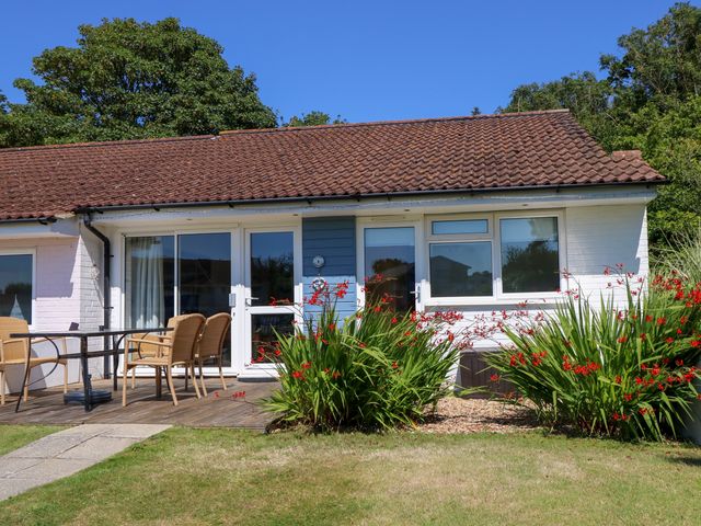 An outdoor patio with a table and chairs in front of a single-story building with sliding glass doors and windows at Cape A1 West Bay Club near Yarmouth