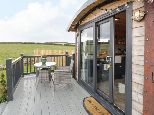 A small deck with a round table and two chairs outside a building with sliding glass doors at Greenacres Carriage in Maybole