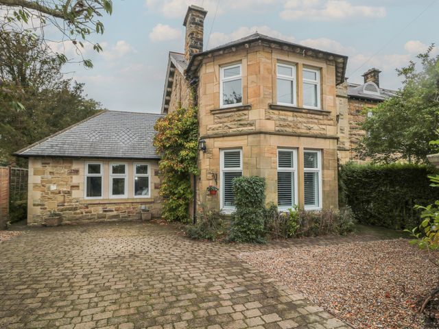 A stone house with multiple windows and a driveway with paving stones and gravel at St Aidans in Alnwick