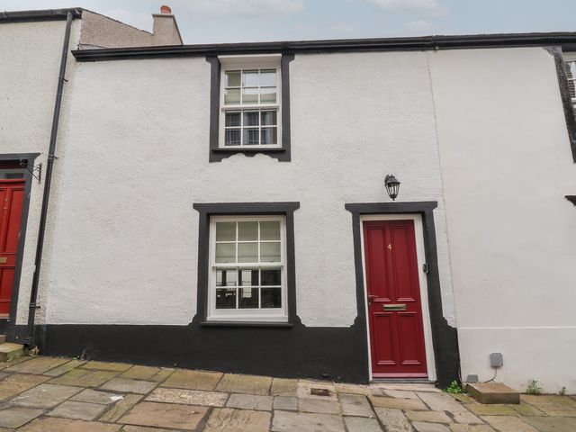 A white house with black trim around windows and a red door numbered 4 at Neptune Cottage in Conwy