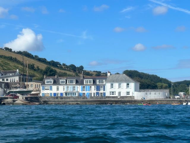 A waterfront with houses facing the sea and hills in the background at Waves End in Mevagissey