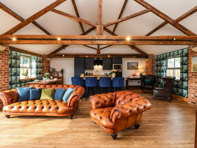 A living room with brown leather sofas blue barstools and exposed wooden beams at Beth's Cottage in East Knapton near Rillington