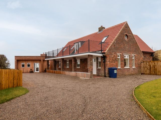 A brick house with a red tiled roof and gravel driveway at The Old Guard House in Goldsborough near Whitby