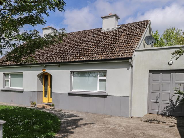 A house with a yellow door gray garage door and a tiled roof at House Of Ireland in Easkey County Sligo