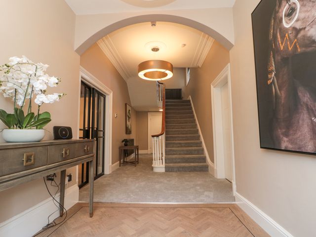 Hallway with carpeted stairs and a wooden console table with a flower pot at Tower View in Scarborough
