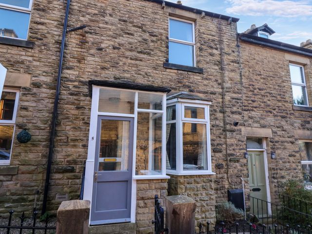 A stone exterior of a terraced house with a gray door and a bay window at 5 Hamilton Terrace in Pateley Bridge