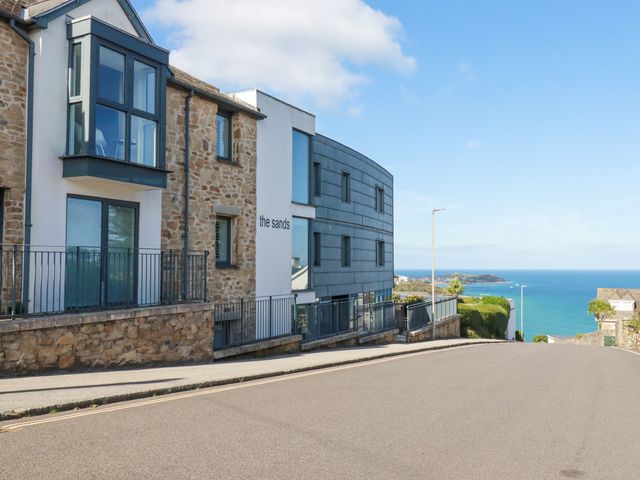 A street view with residential buildings and a distant ocean view at The Sands in Carbis Bay