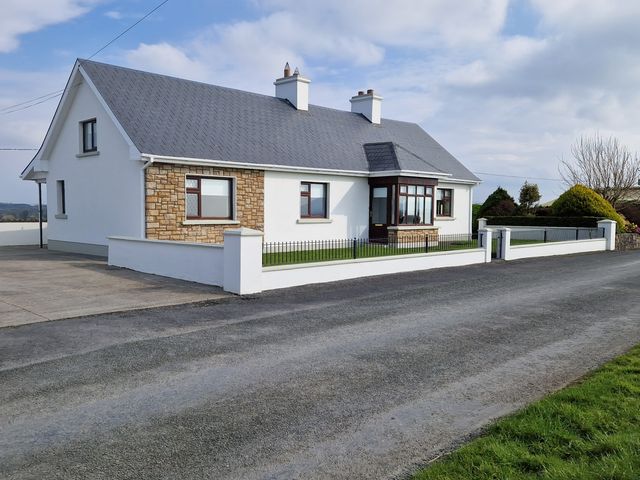 A single story house with a gray roof white walls and stone facade near a road at The Farmstead in Lisconny near Riverstown