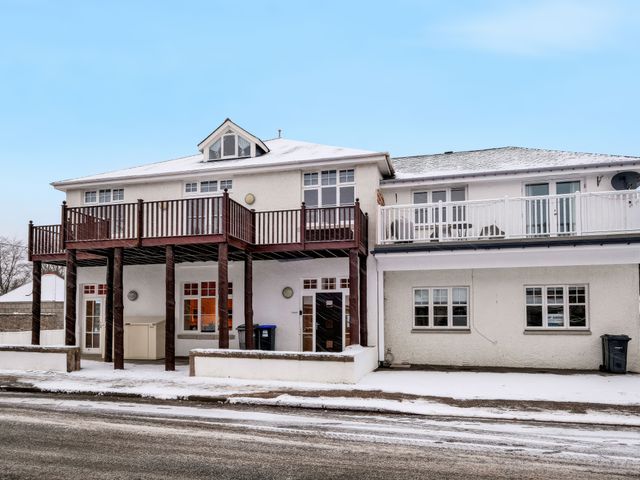 An exterior view of a two-story building with balconies and snow on the ground at Tullich Apartment in Ballater