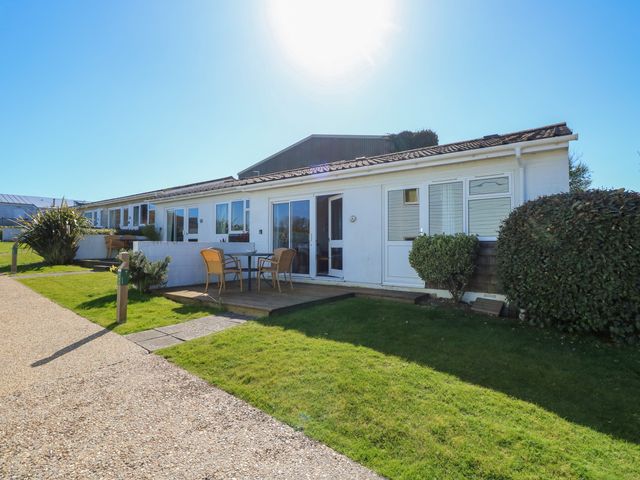 A row of single-story white houses with patios and garden furniture at Cape A9 in Norton Near Freshwater