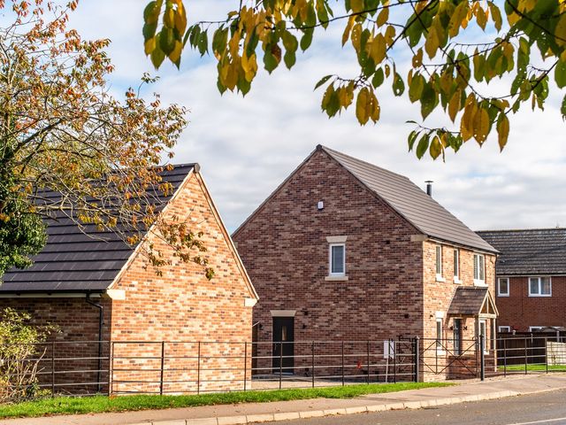 A brick house with a black roof and metal fence at Farm View House in Somerby