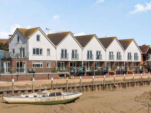 A row of houses with balconies overlooking a dock with a boat at 16 The Boathouse in Rye