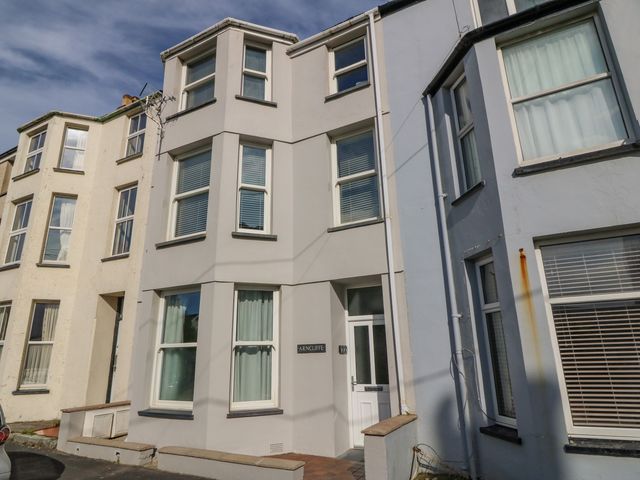 A row of three-story terraced houses with bay windows and a white front door at Y Castell Apartment 2 in Criccieth