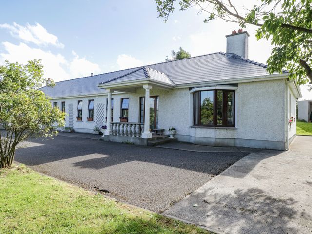 A single story house with a tiled roof and a porch surrounded by trees and a driveway at Belladrihid Cottage Ballysadare near Sligo County Sligo