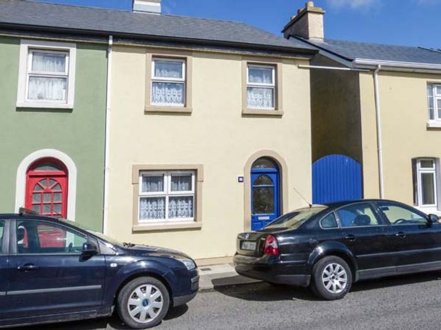 A street view of terraced houses with colored doors and parked cars at High Tide in Belmullet County Mayo