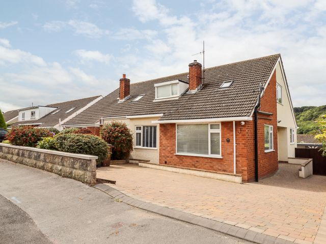 A semi detached house with driveway and shrubs along a stone wall at 4 Bodnant Road in Rhos On Sea