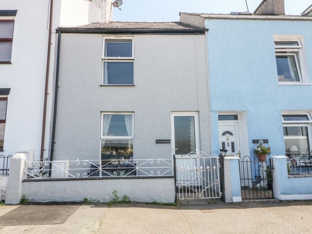 A front view of two connected houses with metal gates and windows at Glan Y Don in Y Felinheli