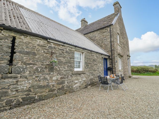 A stone exterior of a house with a blue door and a patio table with four chairs on a gravel surface at Seaview-Barsloisnach Cottage in Kilmartin