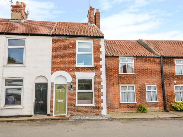 A row of attached brick houses with tile roofs on a street at Coorie Cottage in Martham