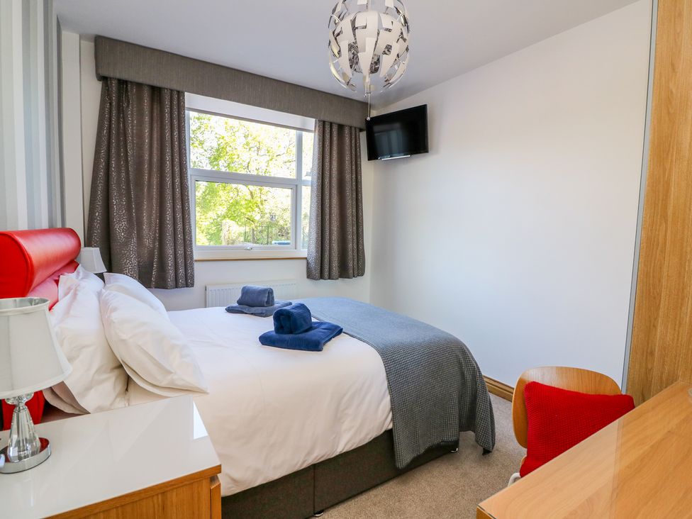 A bedroom with a bed towels on it a desk and a wall mounted television at Ty'r Orsaf in Builth Wells