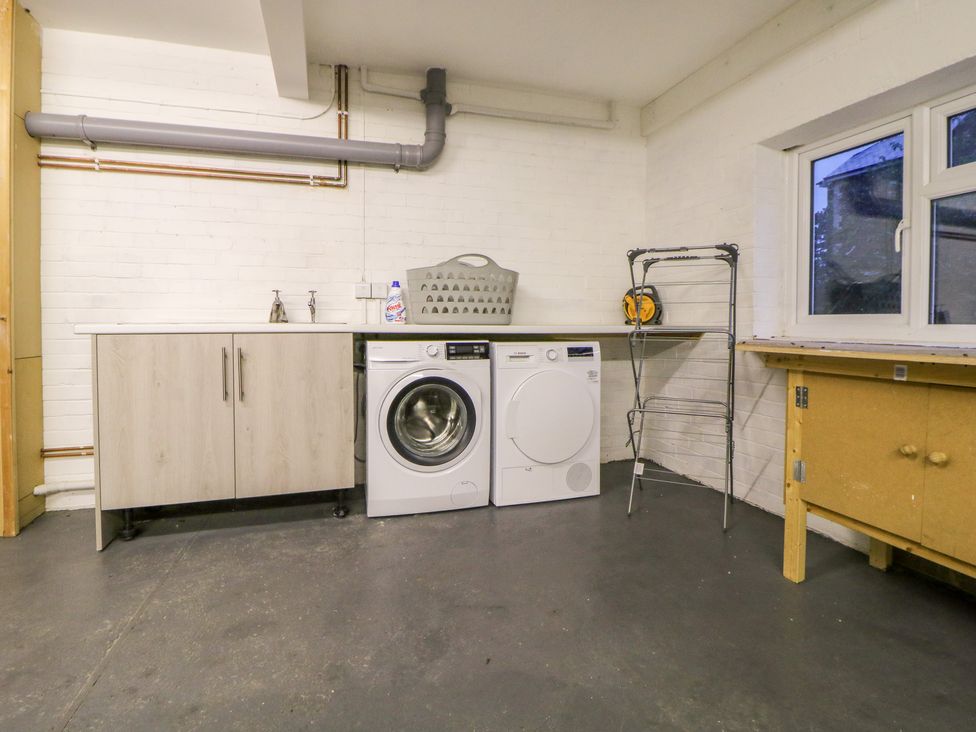 A laundry room with a washing machine dryer drying rack and cabinets at Casalmare in Exmouth