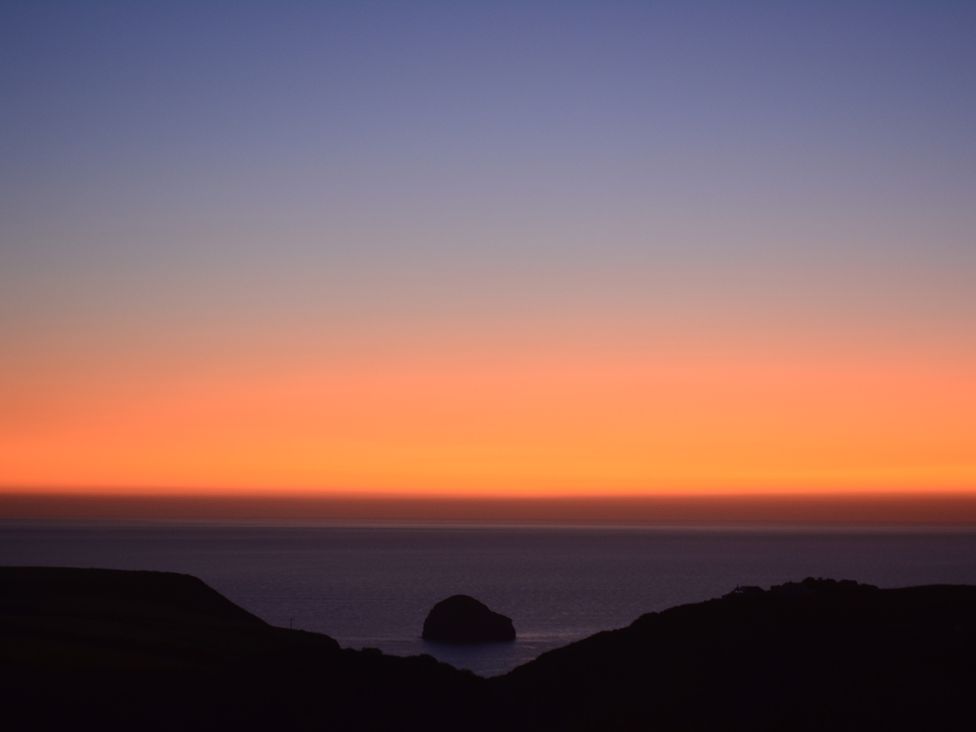 A coastal landscape with a rock formation in the sea at sunset with colorful sky at Glenhaven in Trewarmett near Tintagel
