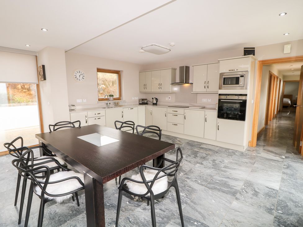 A kitchen with white cabinets a black dining table with six black chairs and a marble floor at House Crohy Head in Dungloe County Donegal