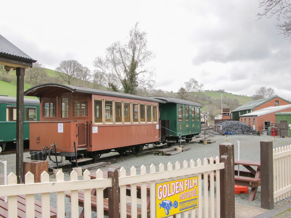 A vintage train carriage at a railway station with hills in the background at The Rhiw in Llanfair Caereinion