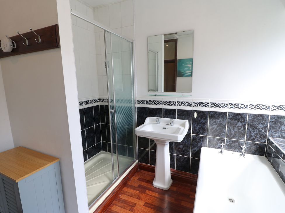 A bathroom with a shower enclosure a pedestal sink a bathtub a mirror and a wooden cabinet at Langlands in Middleton-In-Teesdale