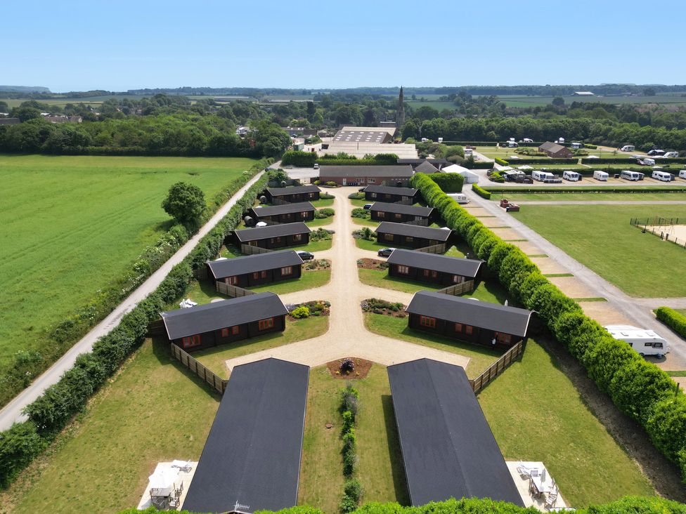 An aerial view of a lodge complex with multiple cabins arranged along a central pathway at Maple Lodge in Greetham Rutland