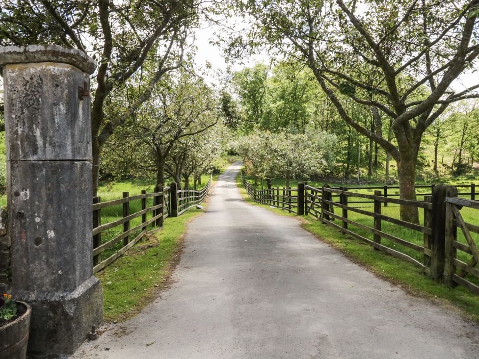 A country road lined with wooden fences and trees at Home Farmhouse Graythwaite near Hawkshead